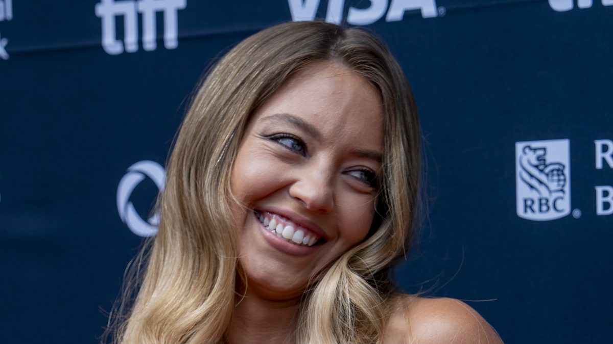 A atriz Sydney Sweeney sorri e olha de lado no tapete vermelho do Festival de Toronto, em setembro de 2025