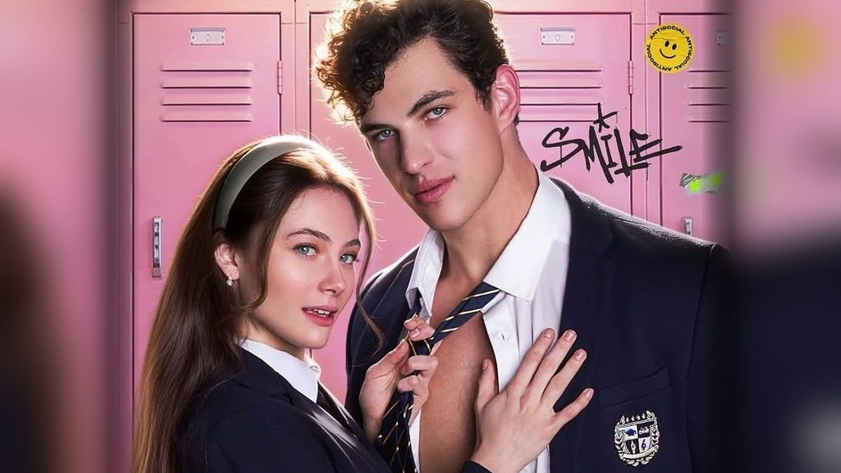 Casal protagonista de A Princesinha e o Bad Boy, de uniforme escolar azul-marinho, diante de armários cor-de-rosa em foto de divulgação