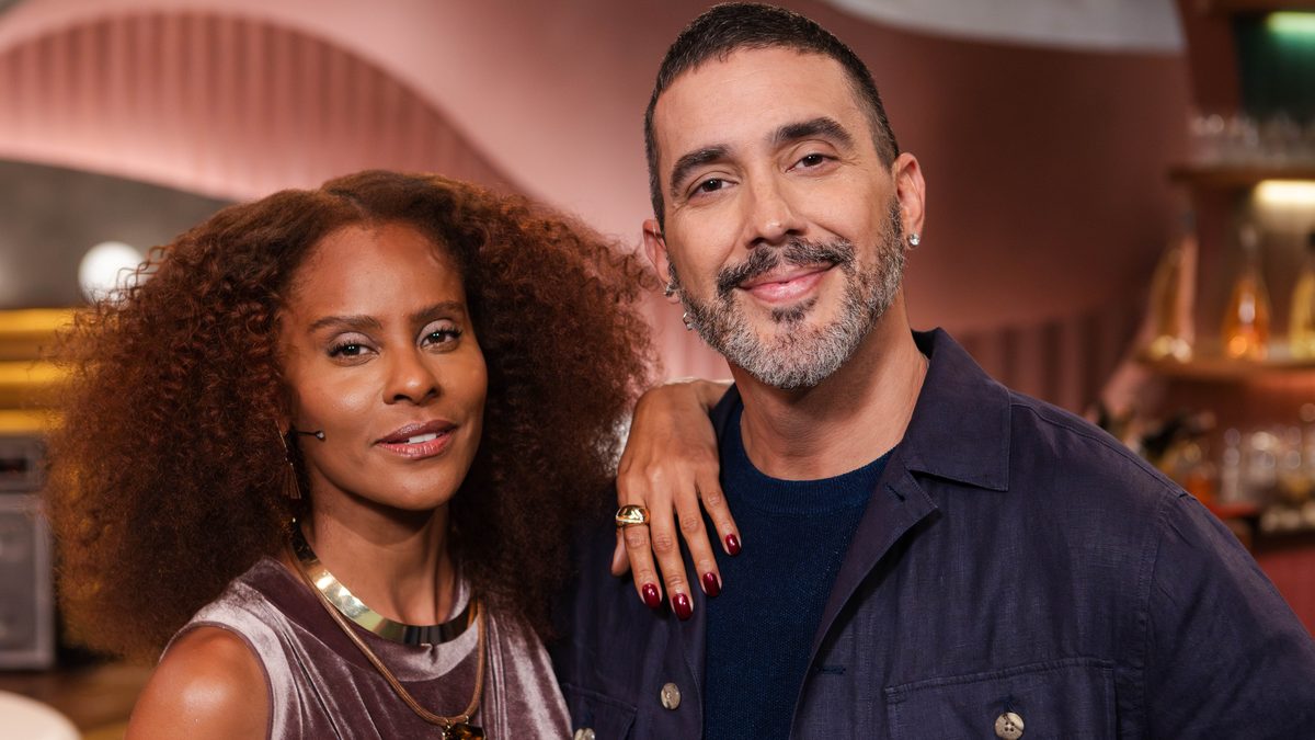 Aline Wirley, de vestido de veludo, e André Marques, de camisa azul-marinho, posam abraçados no cenário do Angélica ao Vivo