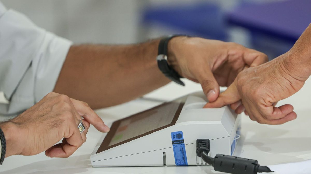 Eleitor coloca o dedo no leitor biométrico do terminal do mesário antes de votar
