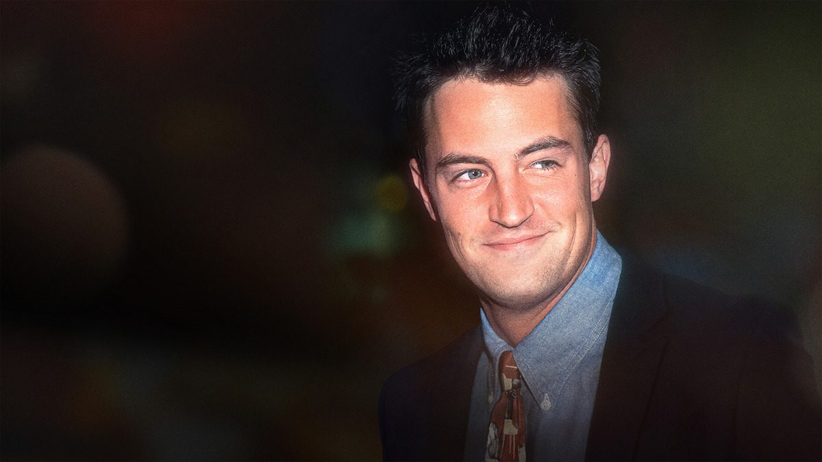 Matthew Perry sorrindo, de camisa azul e paletó escuro, na imagem de divulgação da série documental Aquele Sobre Matthew Perry, da Netflix