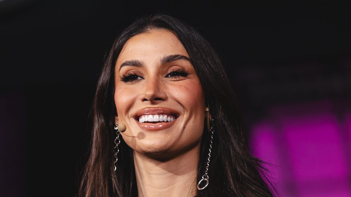 A influenciadora Bianca Andrade, de cabelo solto e microfone de rosto, sorri num palco do Web Summit Rio em 2024