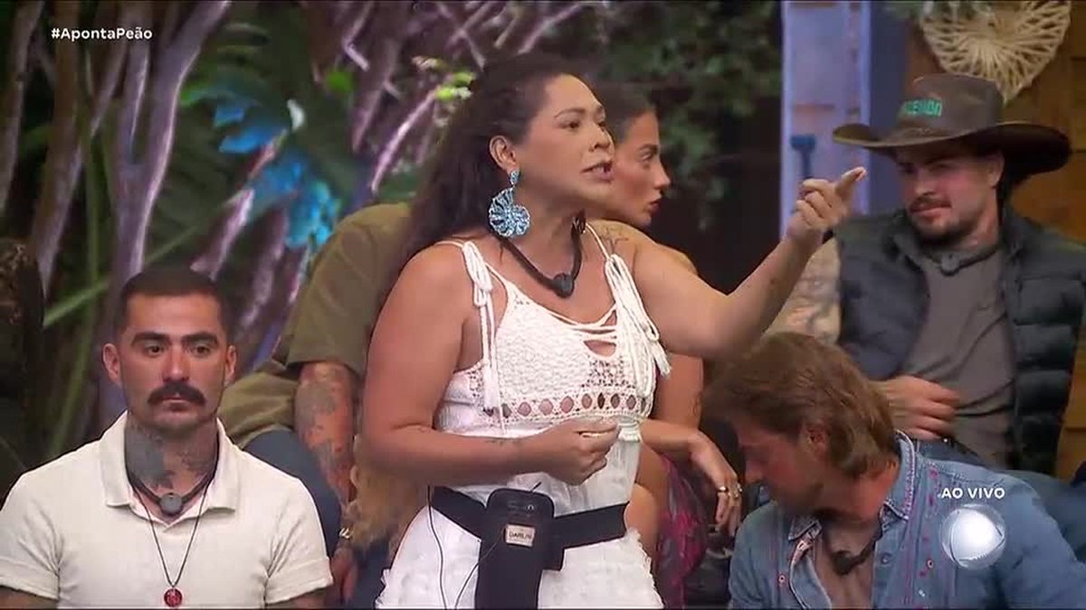Darlin, de blusa branca e dedo em riste, discursa durante o Aponta Peão de A Fazenda 18, com peões sentados ao redor