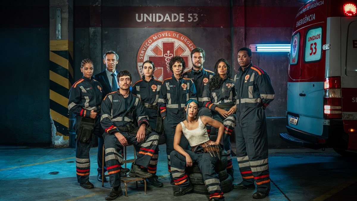 Elenco de Emergência 53 posa de uniforme diante de uma ambulância da Unidade 53, em foto de divulgação do Globoplay