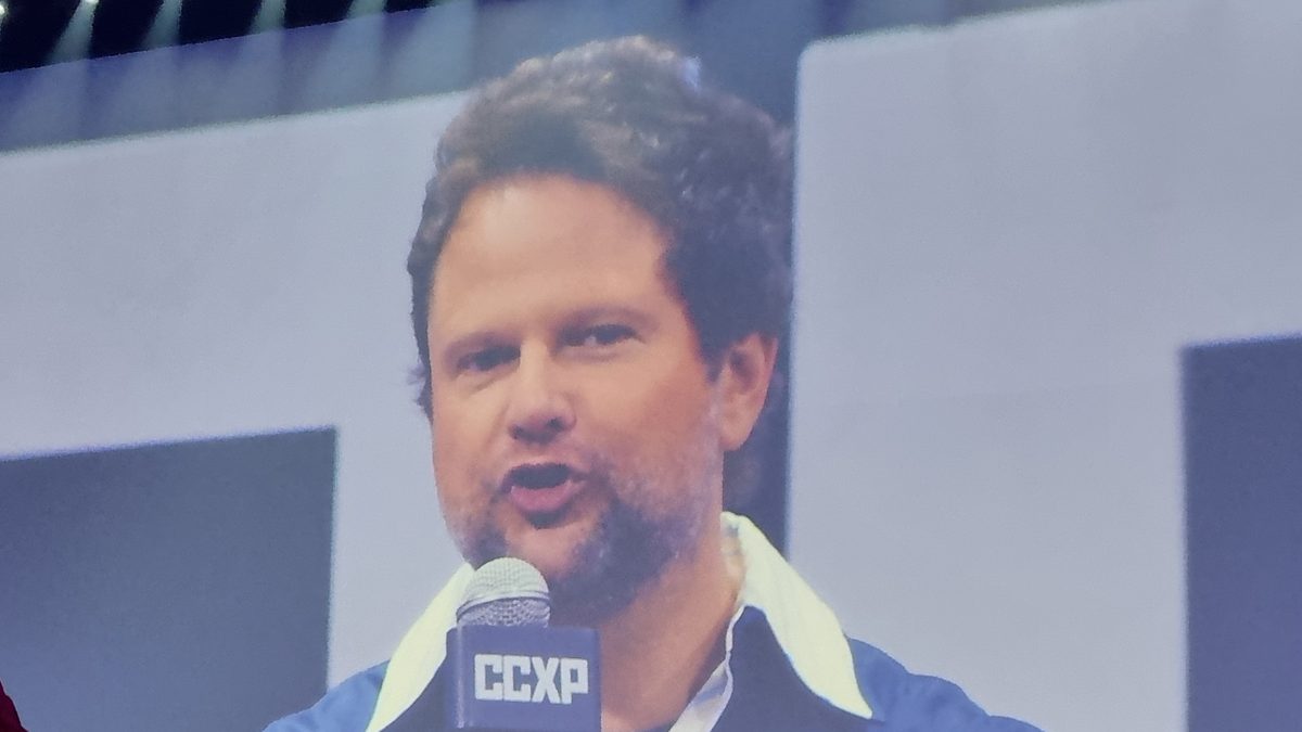 O ator Selton Mello fala ao microfone, projetado no telão de um painel da CCXP 2024, em São Paulo