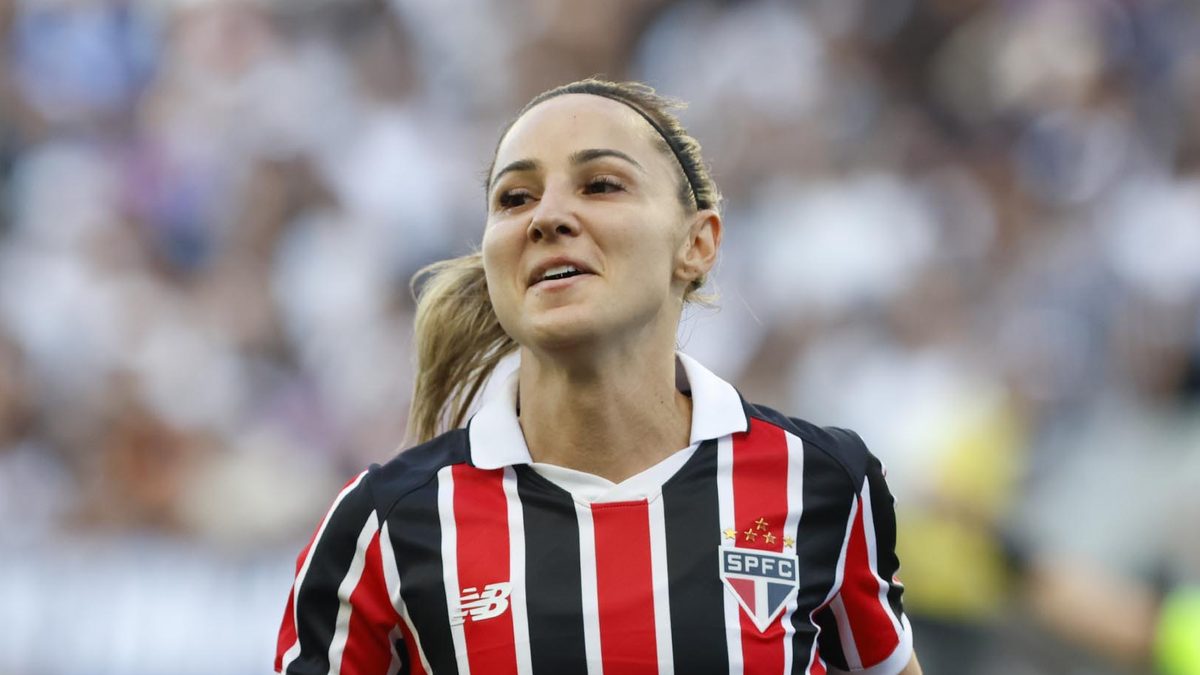 Jogadora do São Paulo, de camisa listrada tricolor, corre sorrindo no jogo de ida da final contra o Corinthians, na Neo Química Arena