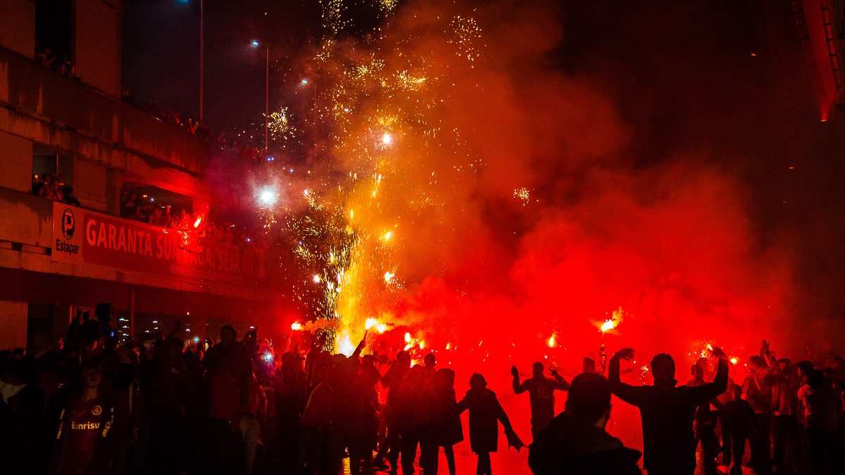 Torcedores do Internacional em silhueta, com sinalizadores vermelhos e fogos, em frente ao Beira-Rio, em Porto Alegre, em foto de 2015
