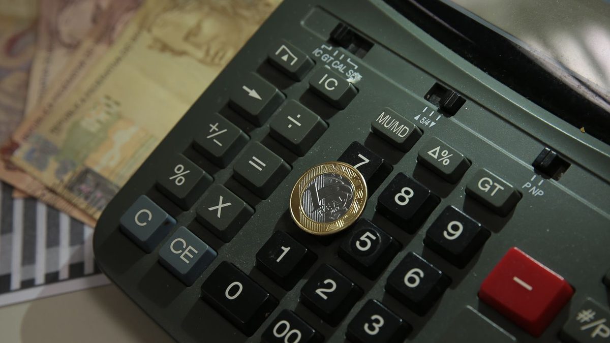 Calculadora com moeda de R$ 1 sobre cédulas de real