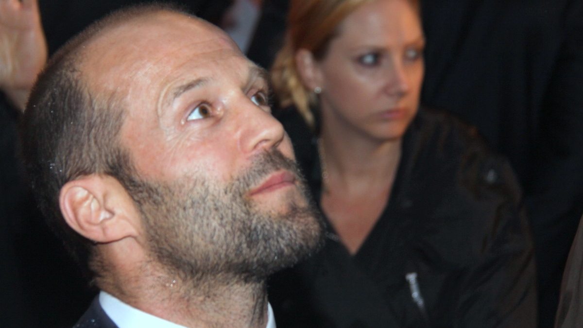 O ator Jason Statham, protagonista de Megatubarão, de barba e terno escuro em evento de Os Mercenários em Berlim, em 2010