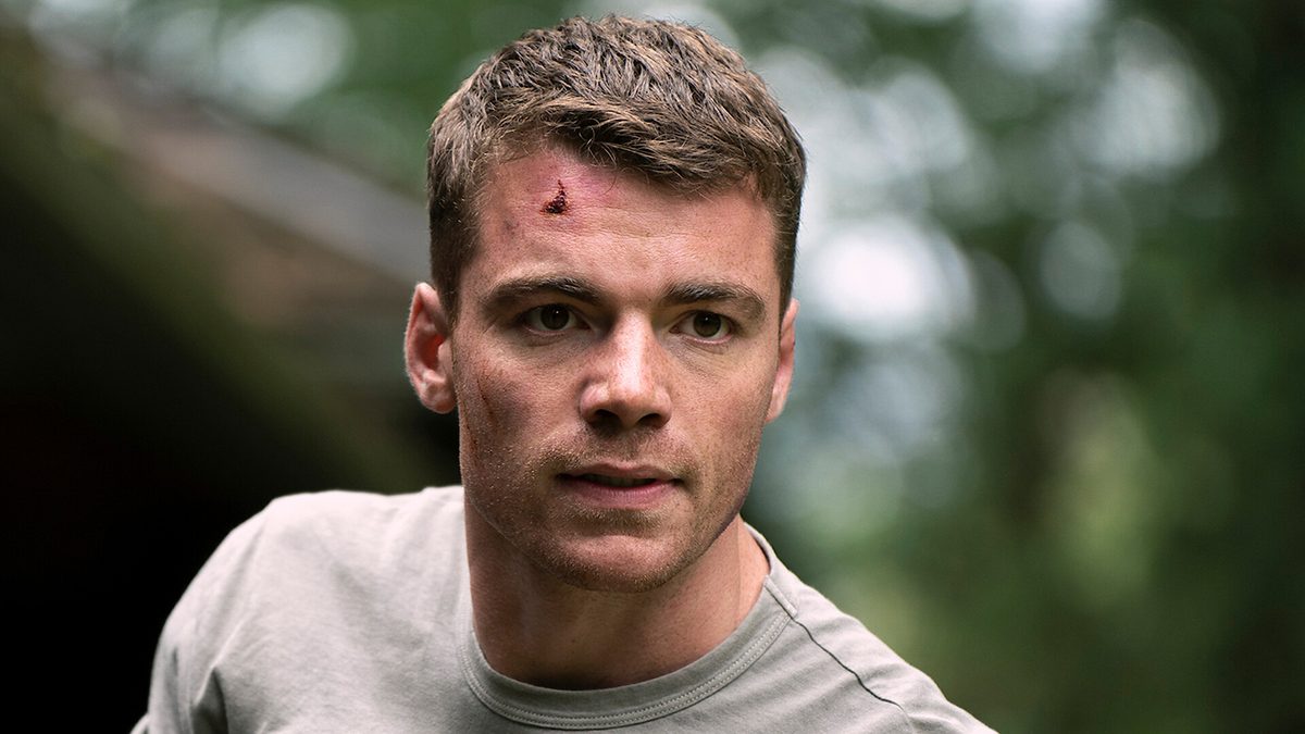Gabriel Basso como o agente Peter Sutherland, com um corte na testa, em cena de O Agente Noturno