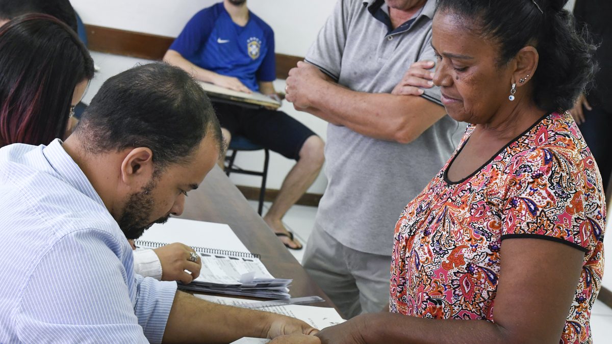 Eleitora em seção eleitoral confere o cadastro com um mesário no primeiro turno das eleições de 7 de outubro de 2018
