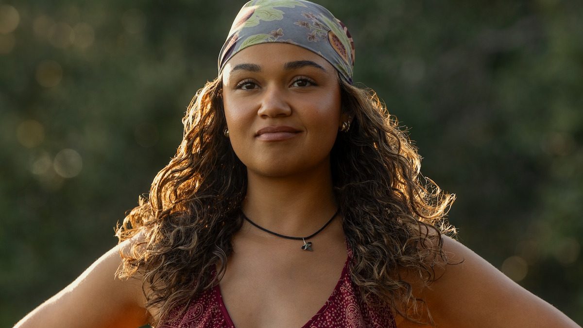 Madison Bailey, a Kiara, de bandana e cabelo cacheado, sorri em imagem de divulgação da temporada 5 de Outer Banks, da Netflix