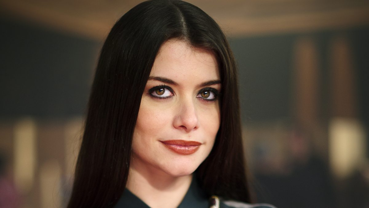A atriz Alinne Moraes, a Vanessa de Por Você, de braços cruzados e camisa escura em foto de 2012