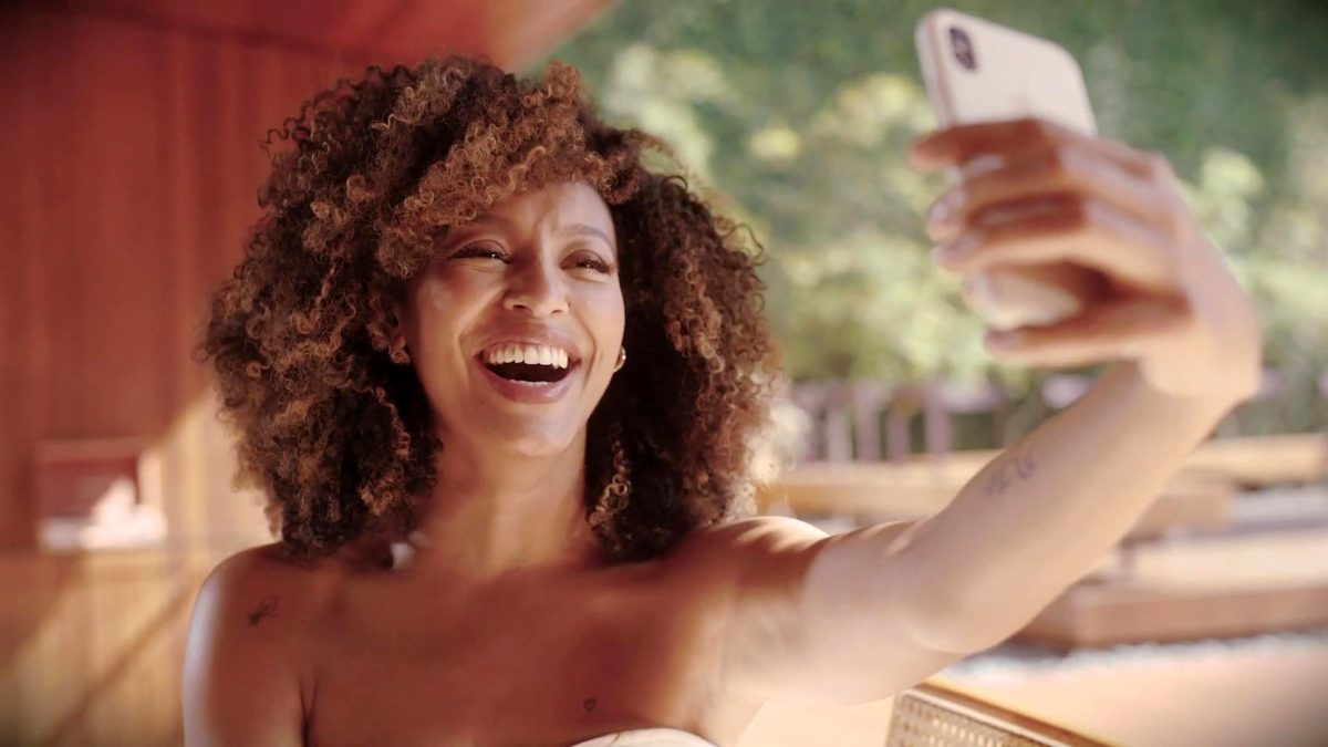 A atriz Sheron Menezzes, a Bela de Por Você, gargalha ao fazer uma selfie em vídeo de campanha de moda de 2021