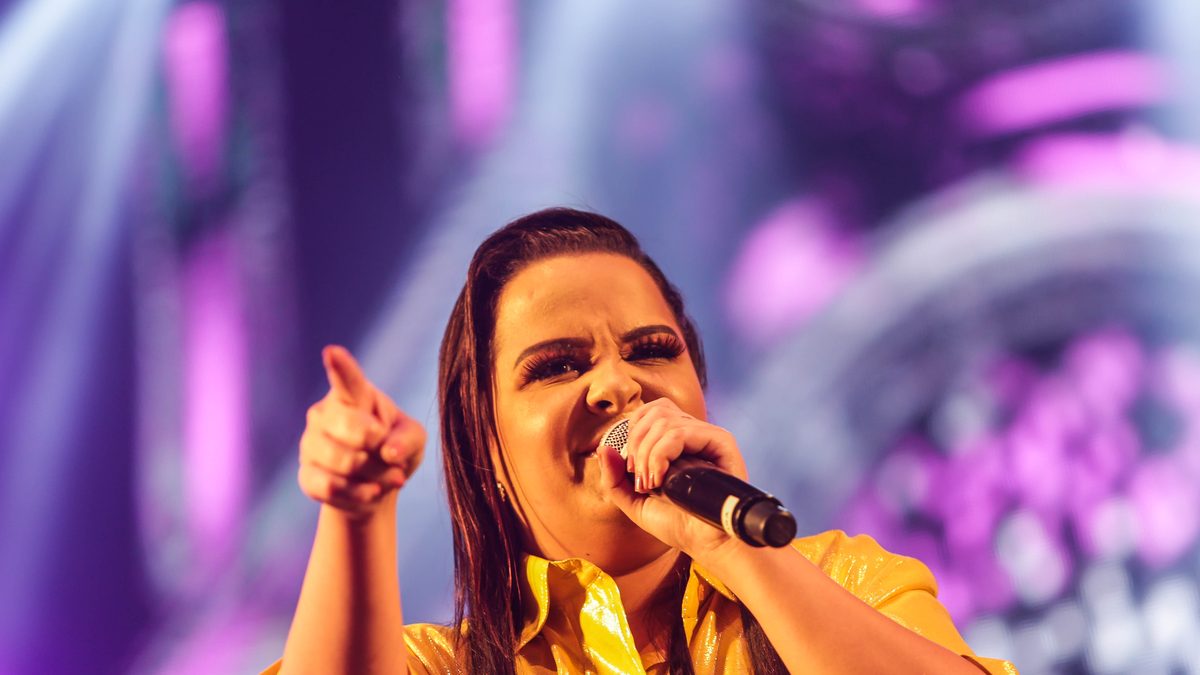 Uma das cantoras da dupla Maiara & Maraisa, de camisa amarela, canta e aponta para o público no show dos 60 anos de Itapevi, em 2019