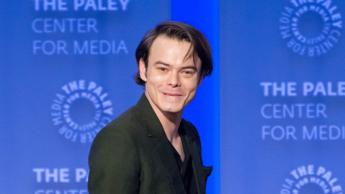 O ator Charlie Heaton, de blazer verde-escuro, sorri para a plateia no painel de Stranger Things no PaleyFest, em Los Angeles, em março de 2018