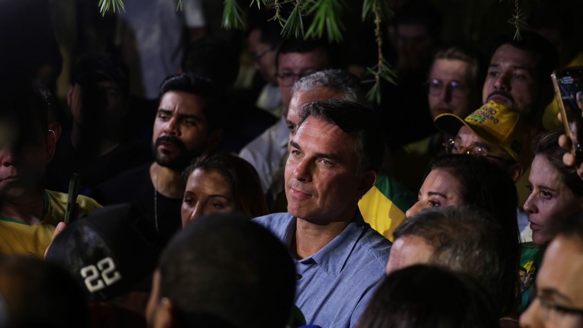 Flávio Bolsonaro entre apoiadores em evento à noite
