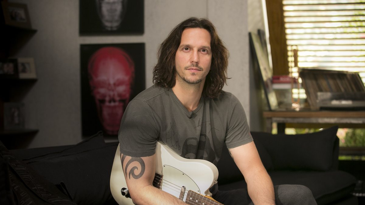 Vladimir Brichta, que faz o roqueiro Gui Santiago em Rock Story, sentado com uma guitarra branca, em foto de divulgação da novela