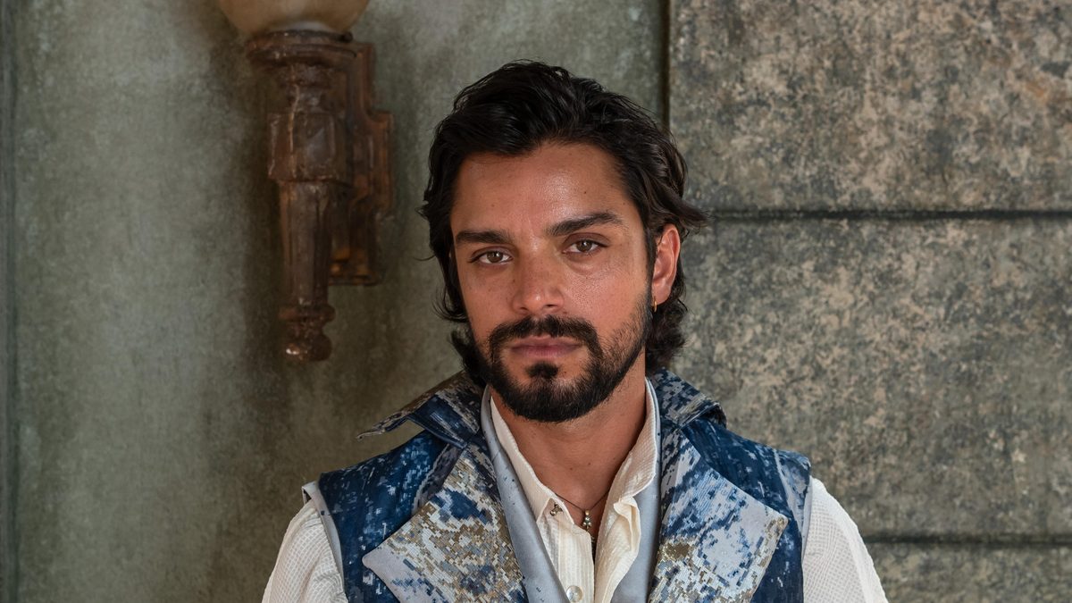 Rodrigo Simas, de barba e cabelo escuro, usa colete azul sobre camisa clara em foto de divulgação do personagem Omar, de A Nobreza do Amor