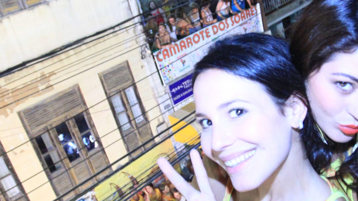 A atriz Juliana Knust, a rainha-mãe Maaca de Reis, sorri e faz o sinal de paz num camarote do Carnaval de Salvador, em 2012