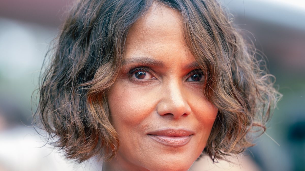 A atriz Halle Berry, de cabelo curto ondulado, sorri de leve para a câmera em um tapete vermelho, em 2025