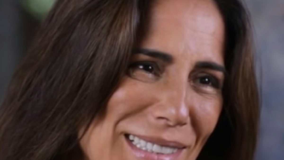 Glória Pires sorrindo, de cabelo escuro e solto, em 2019