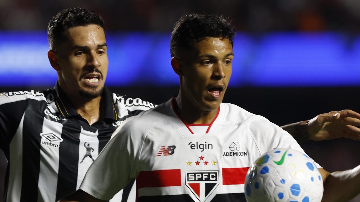 Jogador do São Paulo, de camisa branca, controla a bola de perto enquanto é marcado por um jogador do Santos, de uniforme listrado preto e branco, no jogo da 21ª rodada do Brasileirão no MorumBIS